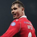 Siriki Dembele z Oxford United je vo vzduchu a Callum Doyle sa kĺže po ihrisku po zákroku.