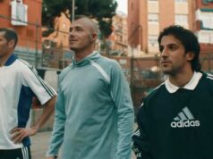 AI David Beckham v oficiálnej reklame Adidas World Cup 2026 s Timothée Chalametom Na ulici stoja vedľa seba traja jednotlivci, pričom každý má na sebe športové dresy inej farby. Za nimi sú viditeľné budovy a zeleň, čo naznačuje mestské prostredie.