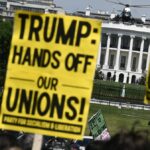 Demonštranti držia znamenia počas prvomájového zhromaždenia, ktoré si pripomína Medzinárodný deň pracujúcich ako Marine One, s americkým prezidentom Donaldom Trumpom na palube, ktorý odchádza z južného trávnika Bieleho domu vo Washingtone, DC, 1. mája 2026. Trump ide na Floridu, aby vystúpil na podujatí v The Villages a zúčastnil sa večere Forum Club of the Palm Beaches