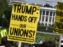 BBC „vynaložila veľké prostriedky na VZŤAŽNENIE NA VZBURY“ pre zamestnancov majstrovstiev sveta, keď sa konali protesty Donalda Trumpa Demonštranti držia znamenia počas prvomájového zhromaždenia, ktoré si pripomína Medzinárodný deň pracujúcich ako Marine One, s americkým prezidentom Donaldom Trumpom na palube, ktorý odchádza z južného trávnika Bieleho domu vo Washingtone, DC, 1. mája 2026. Trump ide na Floridu, aby vystúpil na podujatí v The Villages a zúčastnil sa večere Forum Club of the Palm Beaches
