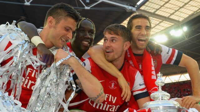 Mathieu Flamini v obleku sa usmieva a pózuje so skríženými rukami