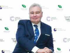 Eamonn Holmes zasadil novú ranu, keď po 19 rokoch „stratil“ úlohu v Man Utd Jednotlivec oblečený vo formálnom obleku a kravate, usmieva sa a sedí na pozadí so vzorom zelených listov a logami.