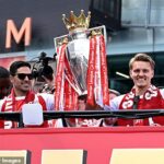 Mikel Arteta a Martin Odegaard držia trofej Premier League na vrchu autobusu