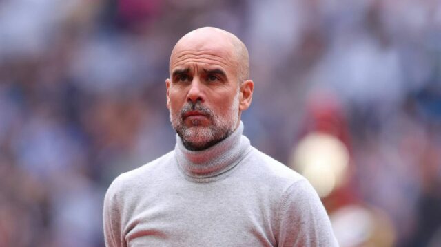 Pep Guardiola sa rozhodol prelomiť mlčanie o „ukončení“ nárokov niekoľko Jednotlivec s holou hlavou, odetý v bielom roláku, stojí v popredí, s rozmazaným publikom viditeľným v pozadí, čo naznačuje formálne alebo profesionálne prostredie.