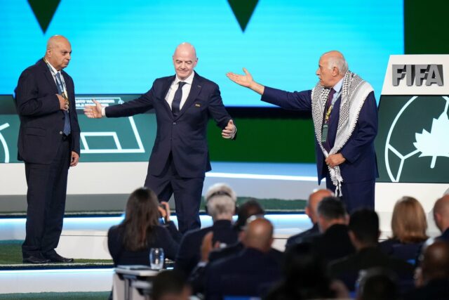 Prezident Palestínskeho futbalového zväzu Jibril Rajoub (vpravo) odchádza od prezidenta FIFA Gianniho Infantina v strede po tom, čo sa odmietol postaviť spolu s viceprezidentom Izraelského futbalového zväzu Basimom Sheikhom Sulimanom, vľavo (AP)