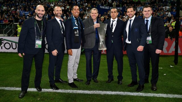 Športoví riaditelia a majitelia Chelsea pózujú s trofejou Conference League