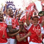 Kapitán Arsenalu Martin Odegaard zdvihol nad hlavu trofej Premier League, keď (L) Jurrien Timber, (2. L) Gabriel Magalhaes, (3. L) Mikel Merino a (R) Declan Rice oslavujú po zápase Premier League medzi Crystal Palace a Arsenalom.