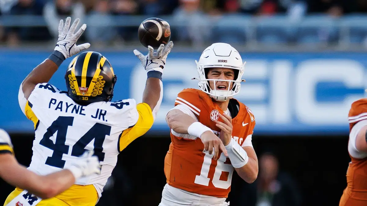 Obranný obranca Michigan Wolverines Damon Payne tipuje prihrávku rozohrávača Texas Longhorns Archa Manninga na Camping World Stadium