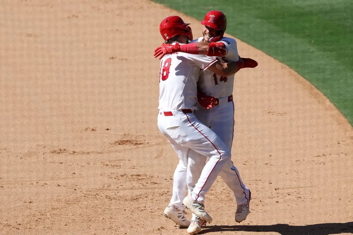 24. júna 2026; Anaheim, Kalifornia, USA; Útočníkovi Los Angeles Angels Loganovi O'Hoppemu (14) blahoželá prvý hráč tímu Nolan Schanuel (18) po vyradenom singli počas desiatej zmeny proti Baltimore Orioles na Angel Stadium. Povinný kredit: Kiyoshi Mio-Imagn Images
