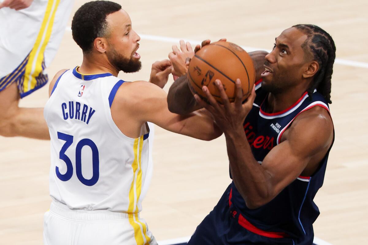Kawhi Leonard z The Clippers (vpravo) sa pokúša vystreliť, zatiaľ čo strážca Warriors Stephen Curry (vľavo) siaha po lopte.