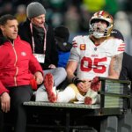 Pevný George Kittle zo San Francisca 49ers sediaci na vozíku na futbalovom ihrisku.
