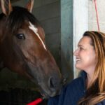 Cherie DeVaux sa usmieva, keď sa Golden Tempo 14. mája 2026 zaťahuje za rukáv kabáta vo svojej stodole na pretekárskej dráhe Keeneland v Lexingtone, Ky.