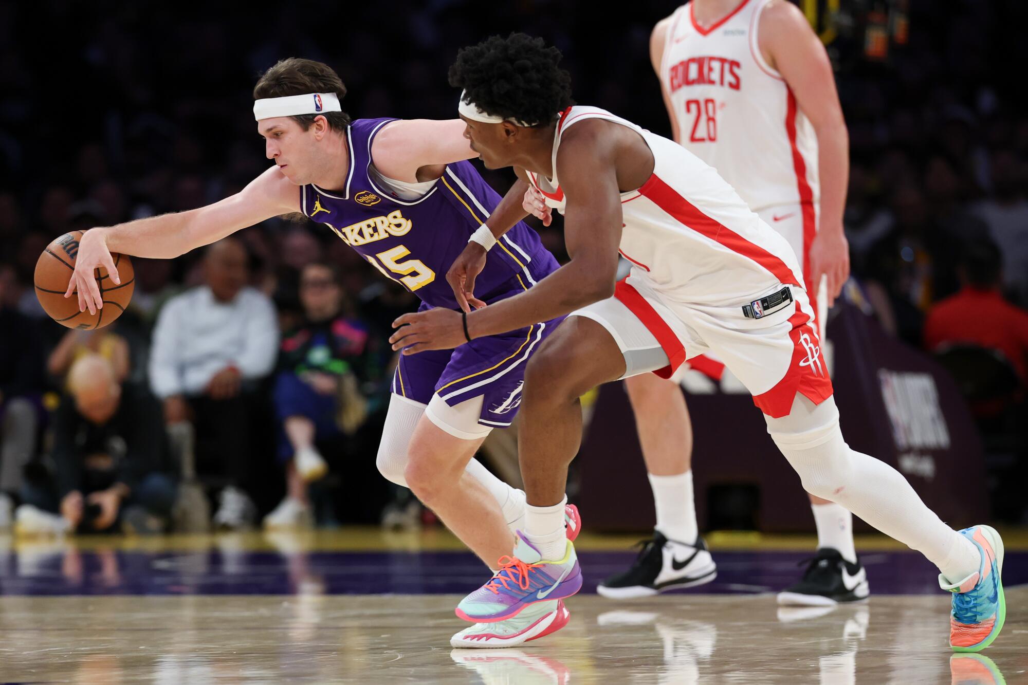 Strážca Lakers Austin Reaves (vľavo) siaha pravou rukou po uvoľnenej lopte pred strážcom Rockets Amenom Thompsonom (vpravo).