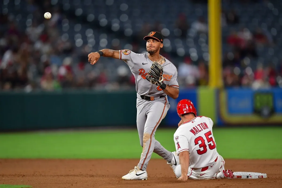 23. júna 2026; Anaheim, Kalifornia, USA; Tretí hráč Los Angeles Angels Donovan Walton (35) je na druhom mieste, keď druhý hráč tímu Baltimore Orioles Jeremiah Jackson (82) hádže na prvé miesto v zápase proti pravému hráčovi v poli Jo Adell (7) počas ôsmej zmeny na Angel Stadium. Povinný kredit: Gary A. Vasquez-Imagn Images