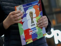 Ponuka nálepiek na Majstrovstvá sveta Panini dáva fanúšikom 112 nálepiek za 4p, keď sa Argos vypredá Osoba oblečená v tmavom saku drží farebnú brožúru s logom Majstrovstiev sveta vo futbale 2026.