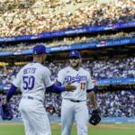 Kraťas Dodgers Mookie Betts, vľavo, a tretí hráč na ihrisku Max Muncy si blahoželajú po defenzívnej hre minulý mesiac.
