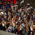 Fanúšikovia bez košele jasajú počas bejzbalového zápasu na štadióne Globe Life Field.