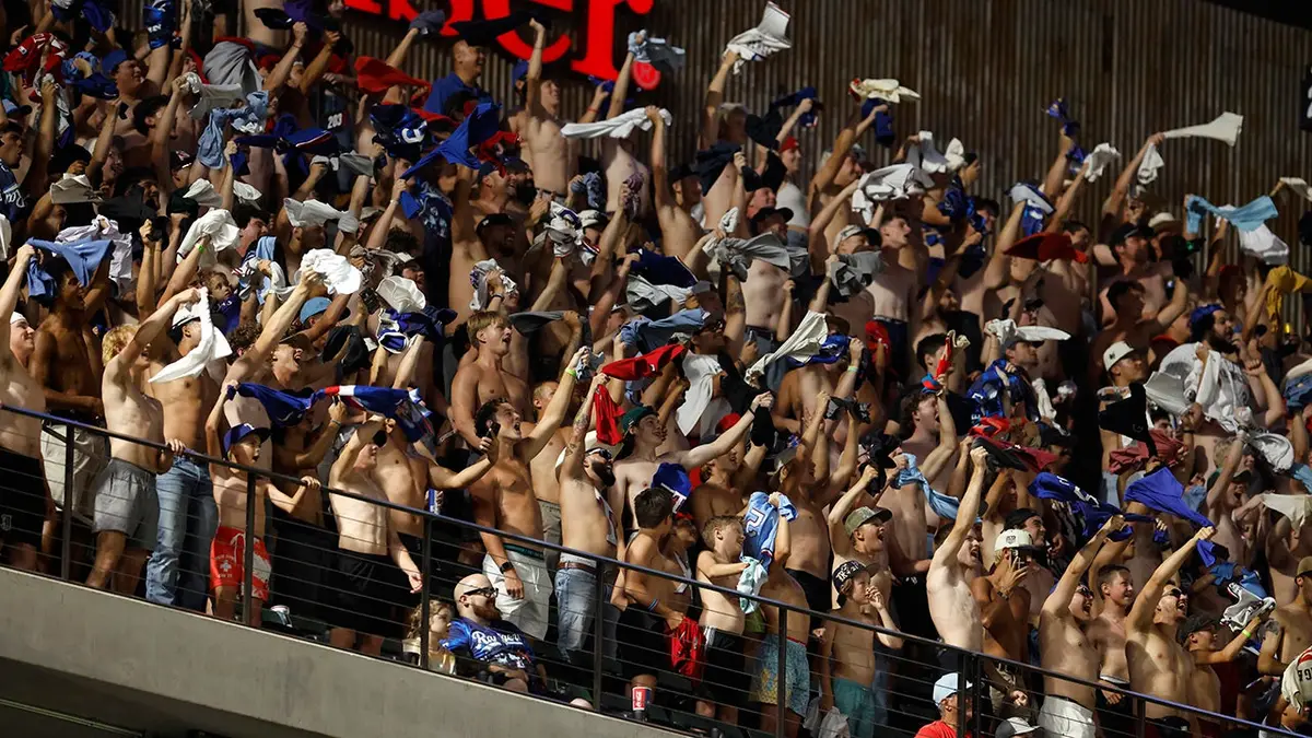Fanúšikovia bez košele jasajú počas bejzbalového zápasu na štadióne Globe Life Field.