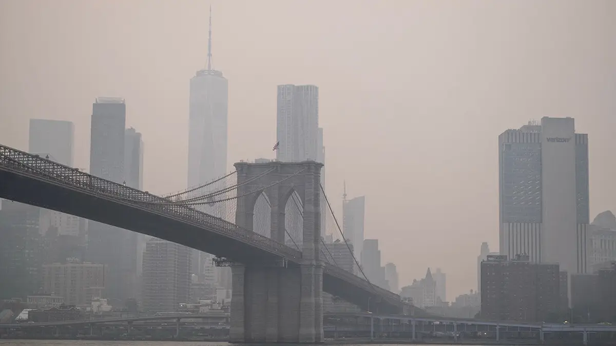 Panorámu Manhattanu nad Brooklynom zahaľuje dym.