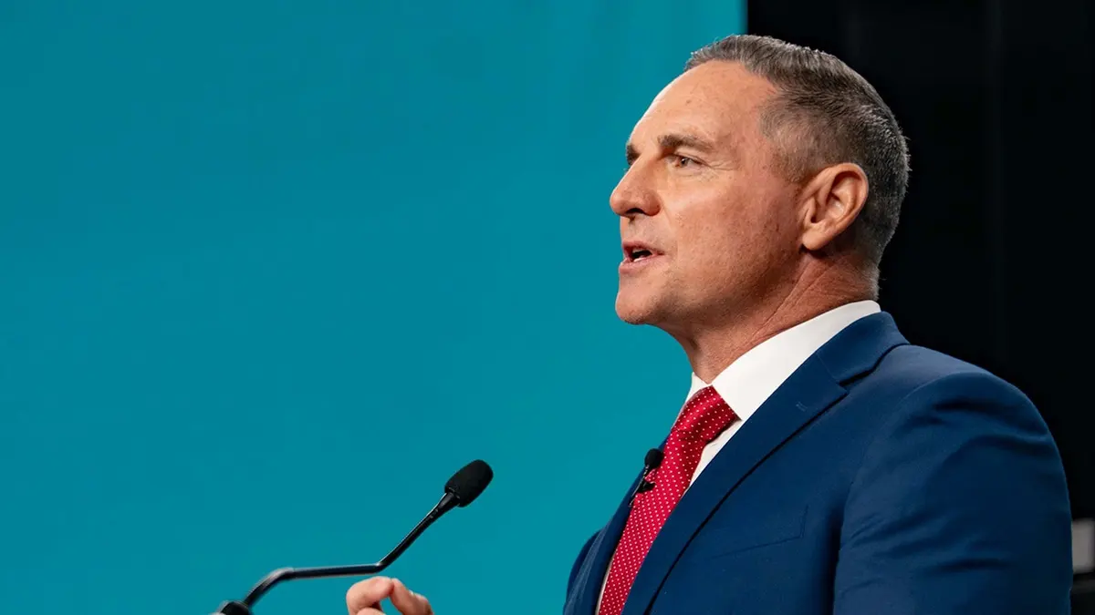 Jay Feely stojí na diskusnom pódiu v štúdiu.