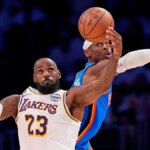 LeBron James preberá prihrávku, keď Shai Gilgeous-Alexander bráni v Los Angeles.