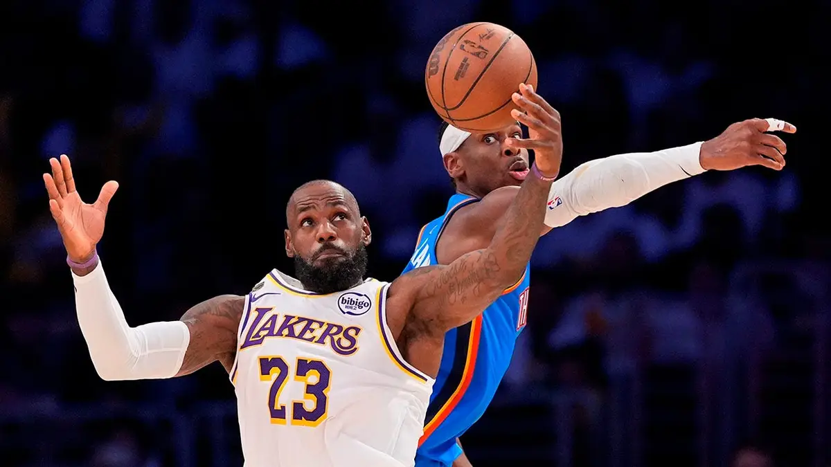 LeBron James preberá prihrávku, keď Shai Gilgeous-Alexander bráni v Los Angeles.