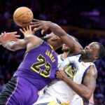 Útočník Lakers LeBron James vľavo sa pokúša skórovať proti útočníkovi Warriors Draymondovi Greenovi, ktorý ťahá Jamesov dres.