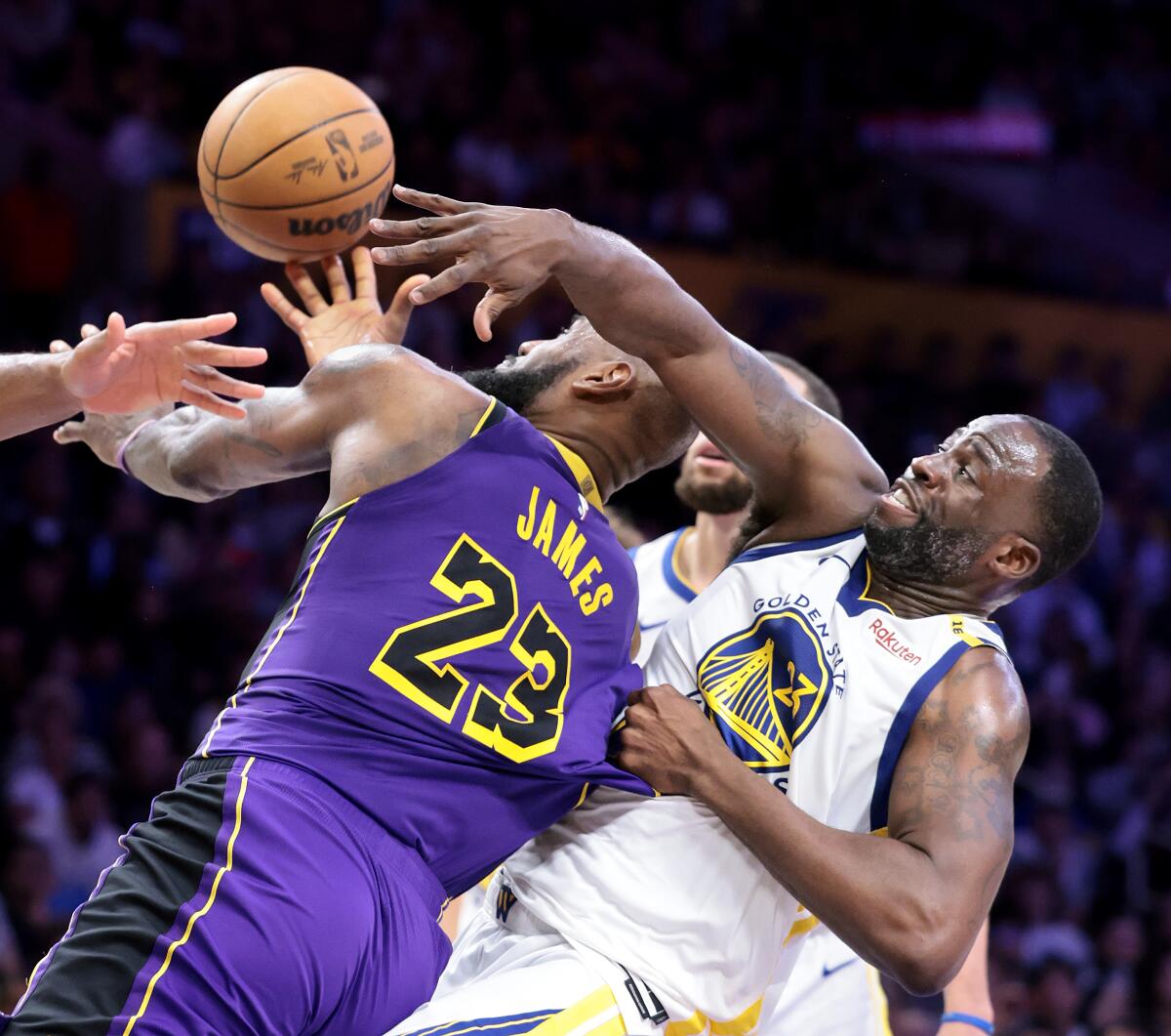Útočník Lakers LeBron James vľavo sa pokúša skórovať proti útočníkovi Warriors Draymondovi Greenovi, ktorý ťahá Jamesov dres.
