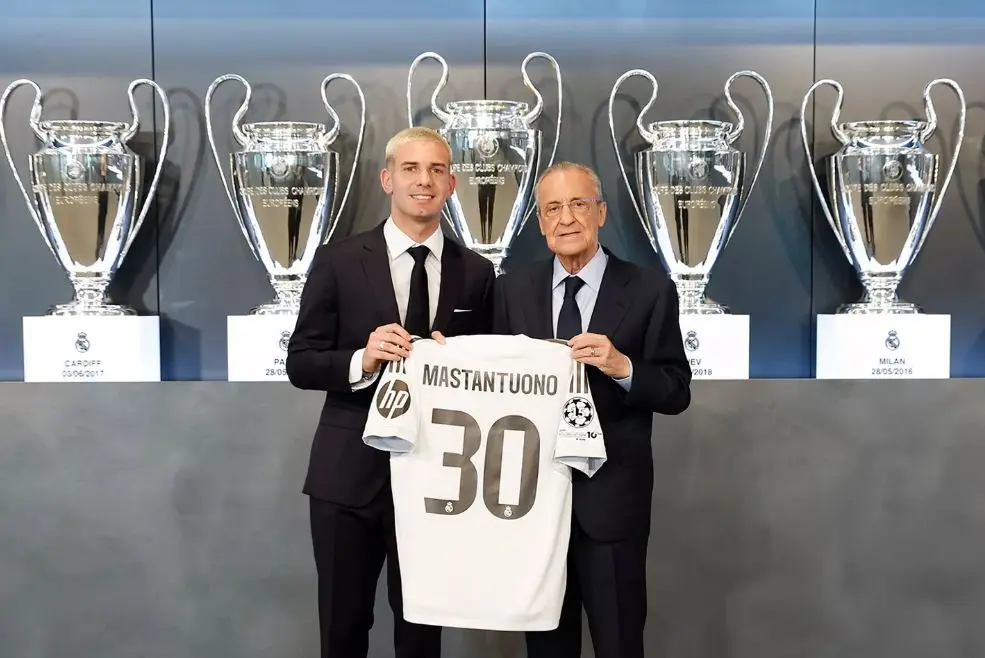 Franco Mastantuono drží dres Realu Madrid s trofejami v pozadí.