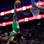 Neemias Queta z Bostonu Celtics, ktorý je hore, si poradil s Kelly Oubre Jr. z Philadelphie 76ers, vpravo, a Joelom Embiidom počas prvej polovice zápasu 4 v prvom kole basketbalovej NBA.