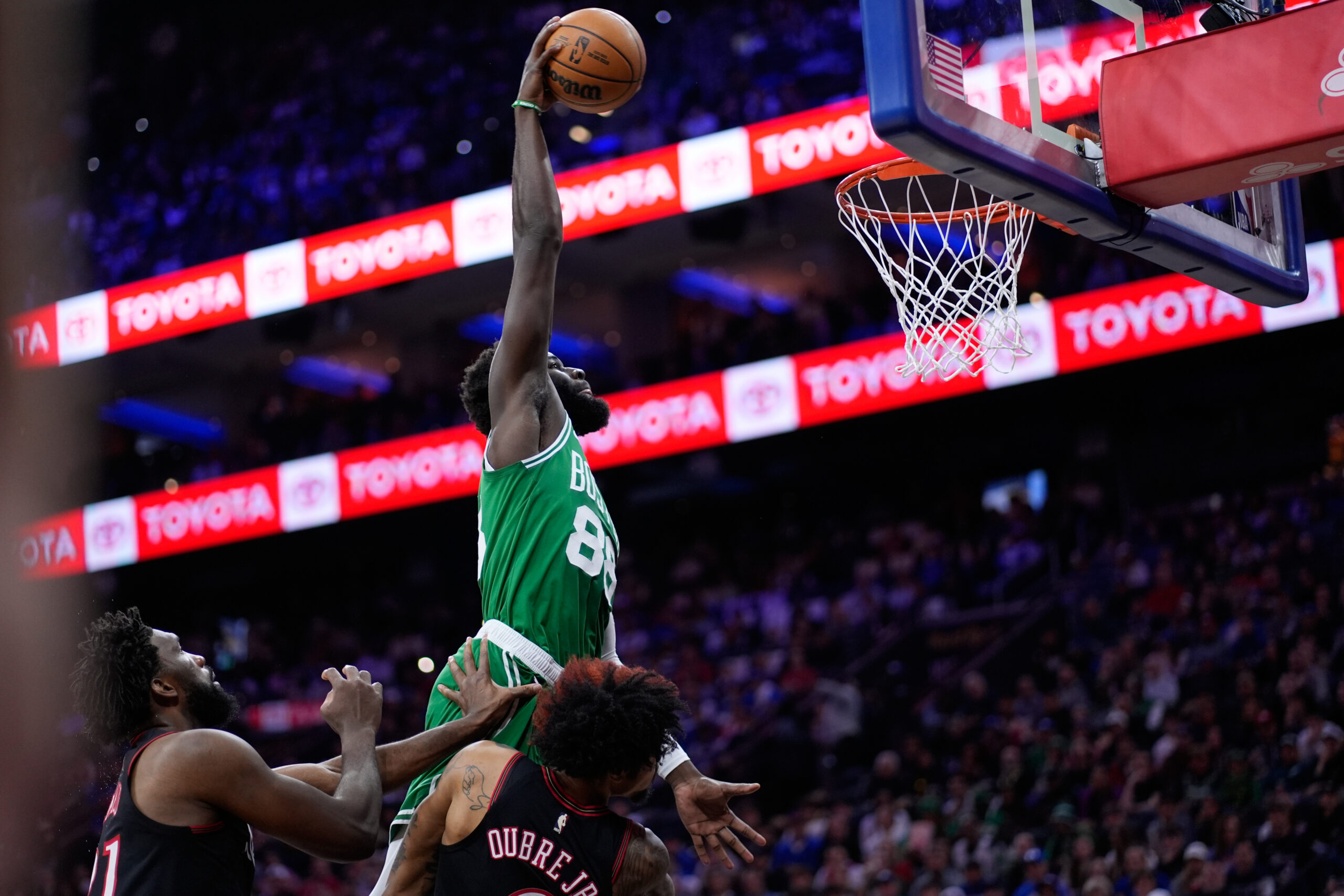 Neemias Queta z Bostonu Celtics, ktorý je hore, si poradil s Kelly Oubre Jr. z Philadelphie 76ers, vpravo, a Joelom Embiidom počas prvej polovice zápasu 4 v prvom kole basketbalovej NBA.