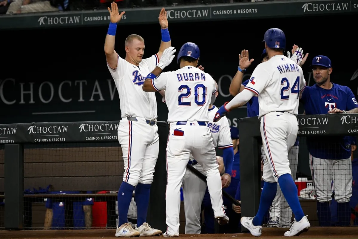 9. júla 2026; Arlington, Texas, USA; Krátkodobý stopér Texas Rangers Ezequiel Duran (20) a pravý hráč v poli Brandon Nimmo (24) a tretí hráč na ihrisku Josh Jung (6) oslavujú po tom, čo Duran zaútočil na dva body proti Los Angeles Angels počas tretej zmeny na Globe Life Field. Povinný kredit: Jerome Miron-Imagn Images