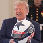 Prezident Donald Trump reaguje a drží prilbu v Bielom dome.