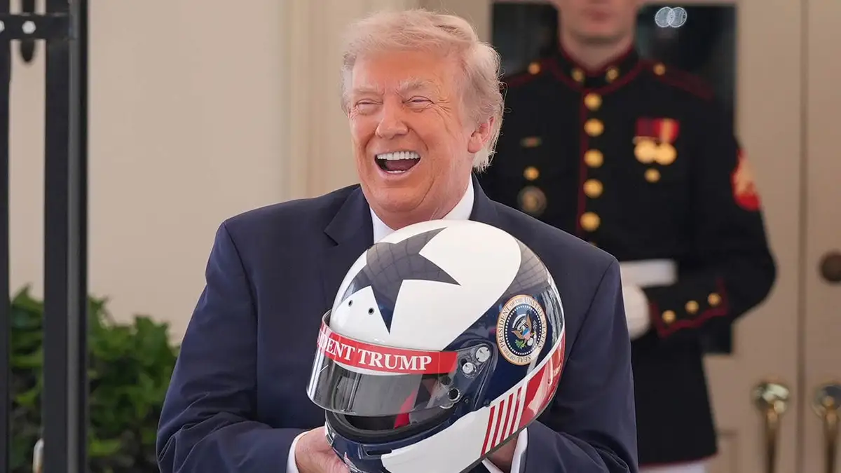 Prezident Donald Trump reaguje a drží prilbu v Bielom dome.