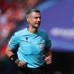 Rozhodca v modrom drese, ktorý riadi futbalový zápas.
