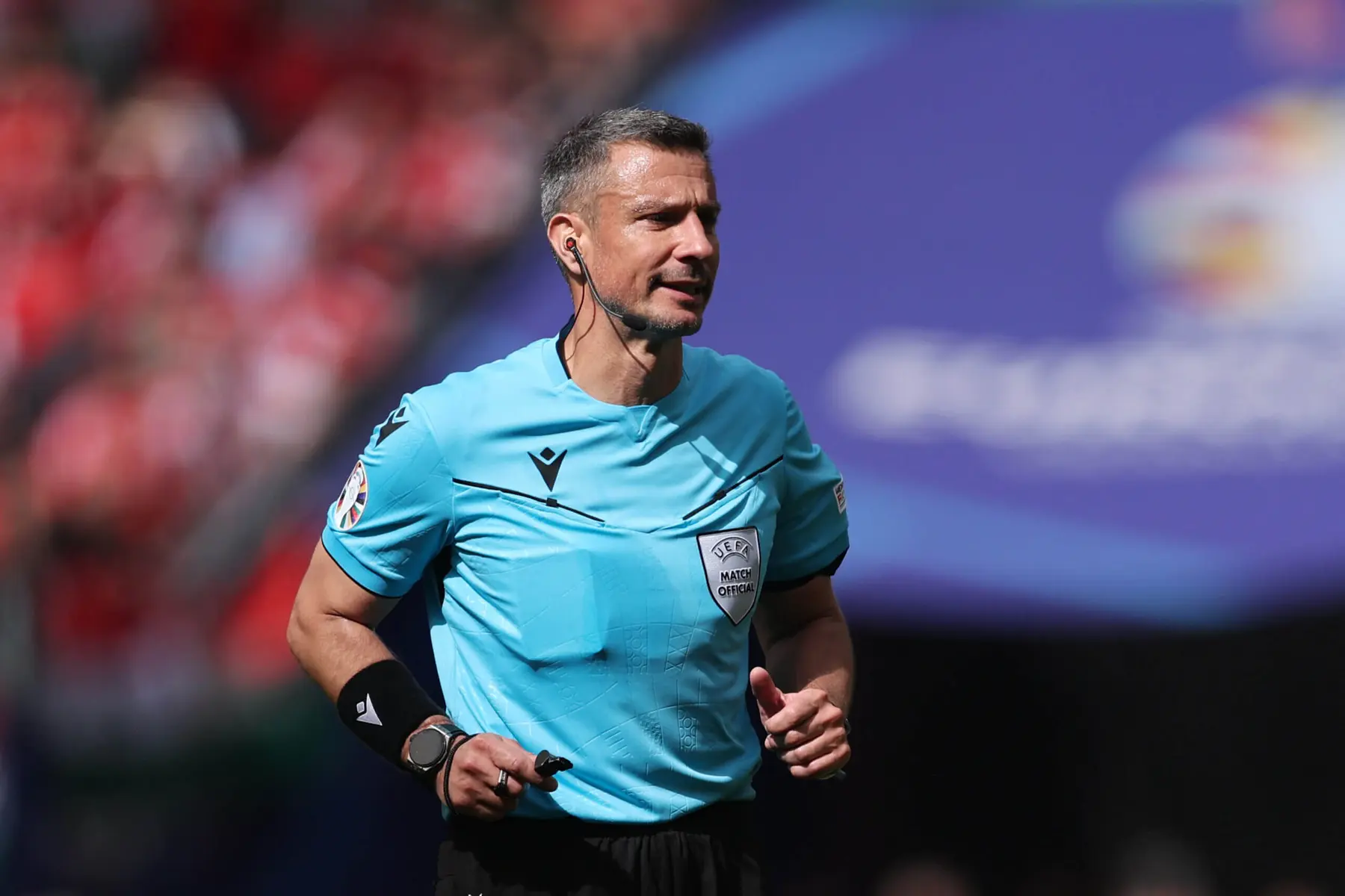 Rozhodca v modrom drese, ktorý riadi futbalový zápas.